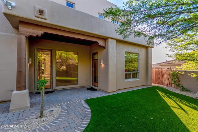 doorway to property featuring a patio area and a lawn