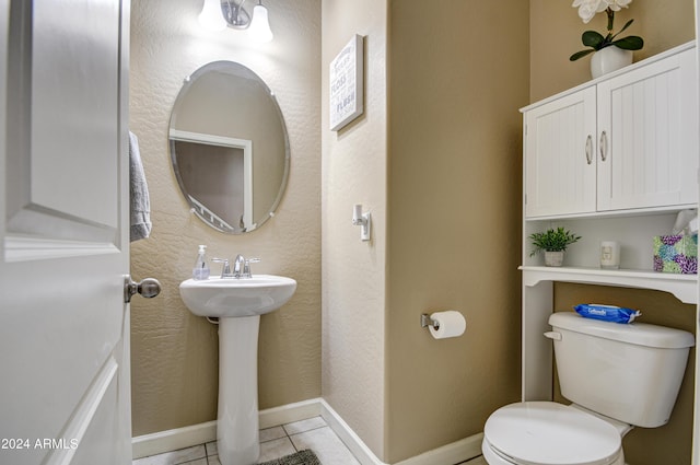 bathroom featuring tile patterned floors, toilet, baseboards, and a sink