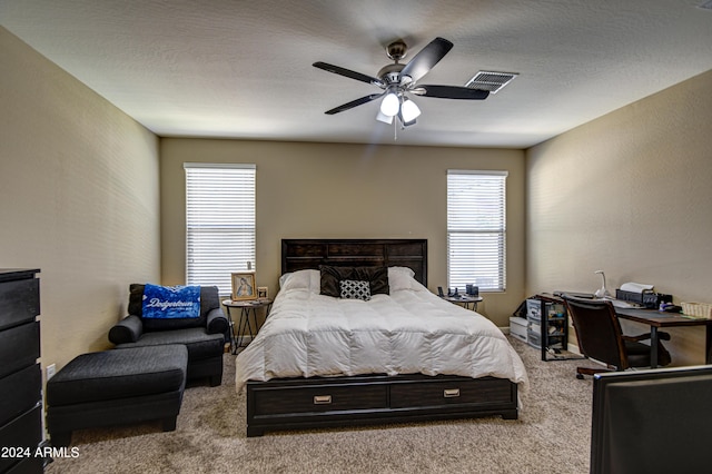 bedroom featuring visible vents, a textured ceiling, carpet flooring, and a ceiling fan