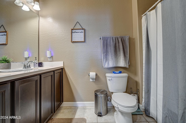 bathroom with toilet, tile patterned flooring, baseboards, vanity, and a textured wall