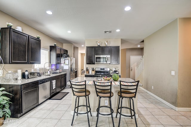 kitchen with visible vents, a breakfast bar, light tile patterned flooring, a sink, and appliances with stainless steel finishes