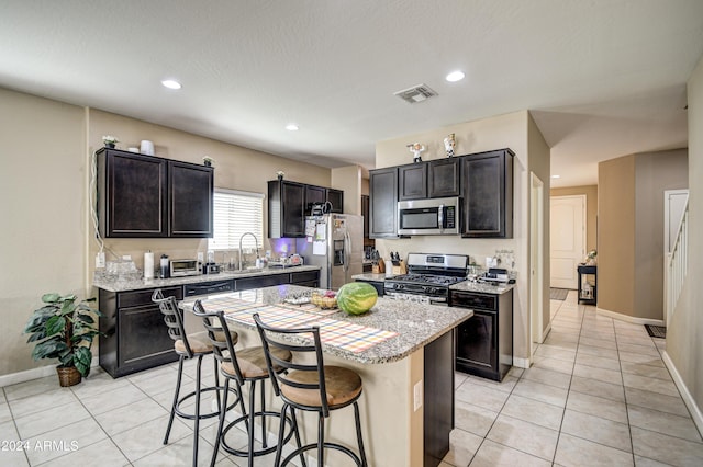 kitchen featuring visible vents, a sink, stainless steel appliances, a kitchen breakfast bar, and a center island