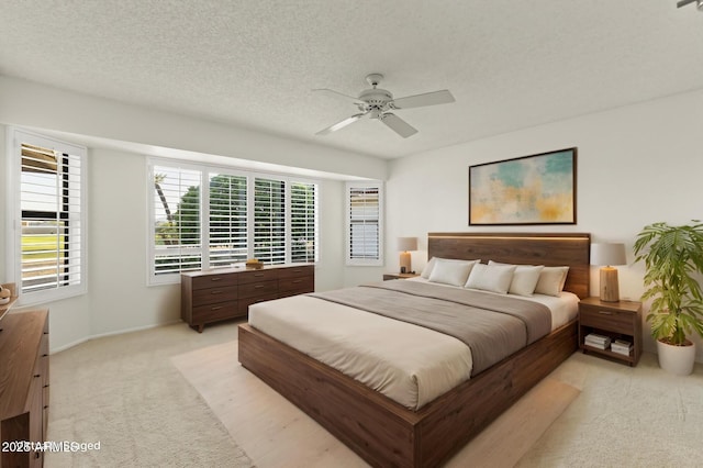 bedroom with a textured ceiling, ceiling fan, light colored carpet, and baseboards