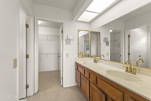 bathroom with a walk in closet, double vanity, and a sink
