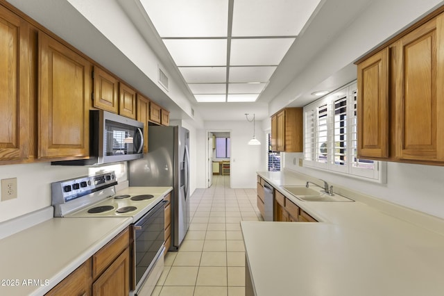 kitchen featuring light tile patterned floors, appliances with stainless steel finishes, light countertops, brown cabinets, and a sink
