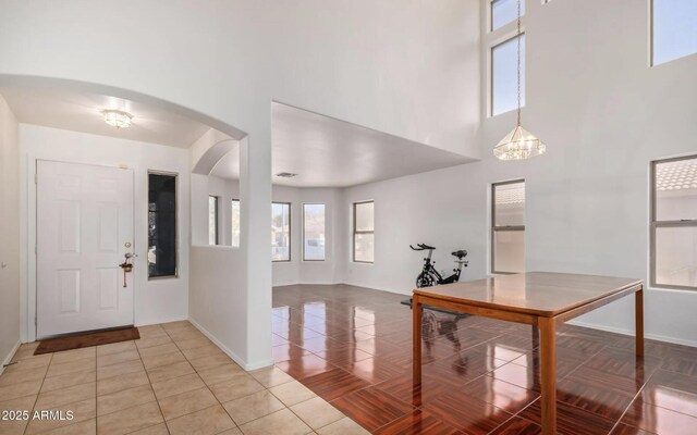 1805 E Aloe Pl, Chandler, AZ 85286 - foyer entrance featuring light tile patterned floors, baseboards, visible vents, arched walkways, and a towering ceiling