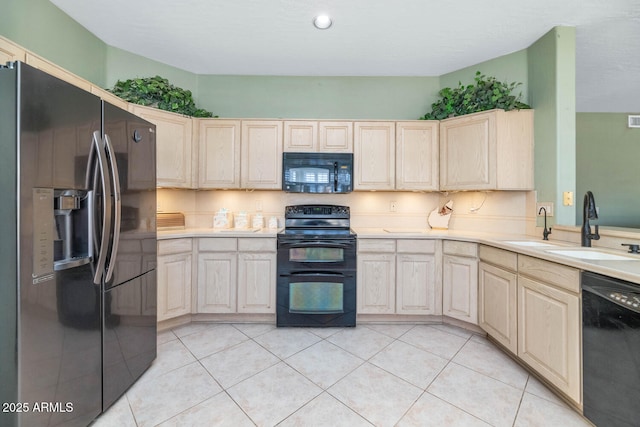 kitchen with light countertops, light brown cabinets, a sink, and black appliances