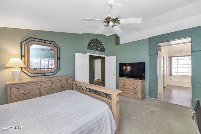 bedroom featuring ensuite bathroom, ceiling fan, light colored carpet, and lofted ceiling