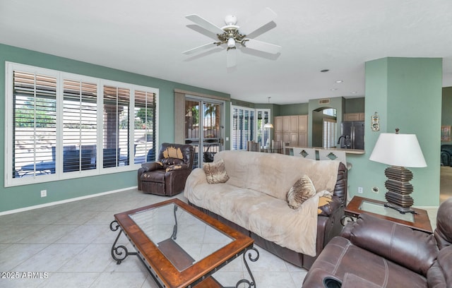 living room featuring ceiling fan, baseboards, and light tile patterned floors