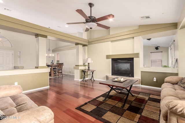 living area featuring a glass covered fireplace, baseboards, visible vents, ceiling fan with notable chandelier, and wood finished floors
