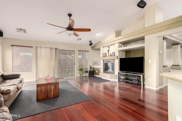 living room with wood finished floors, a glass covered fireplace, a ceiling fan, and visible vents