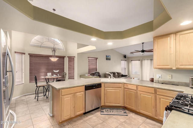 kitchen featuring a peninsula, light brown cabinetry, light countertops, stainless steel appliances, and open floor plan
