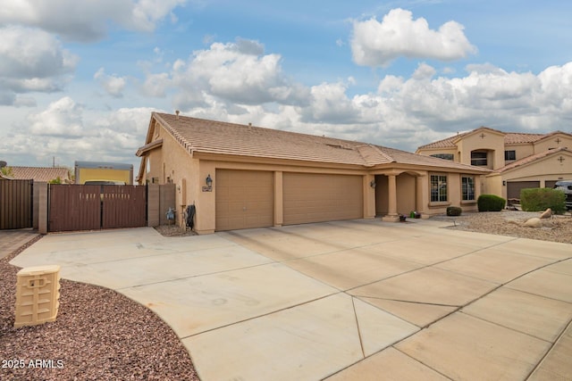 view of front facade with a tiled roof, a garage, stucco siding, a gate, and driveway