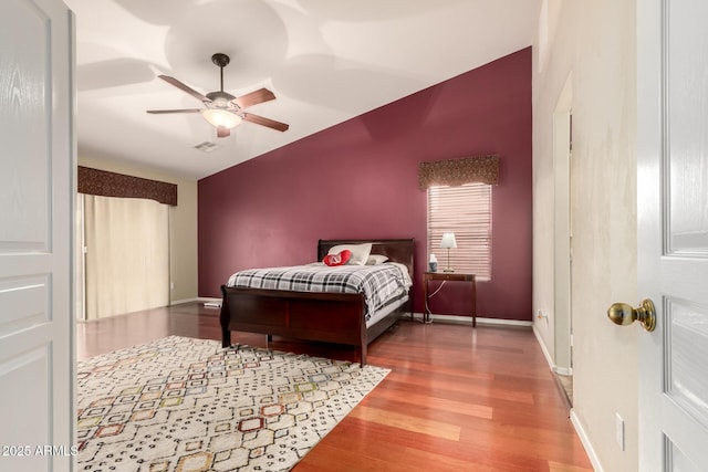 bedroom featuring wood finished floors, visible vents, baseboards, and lofted ceiling