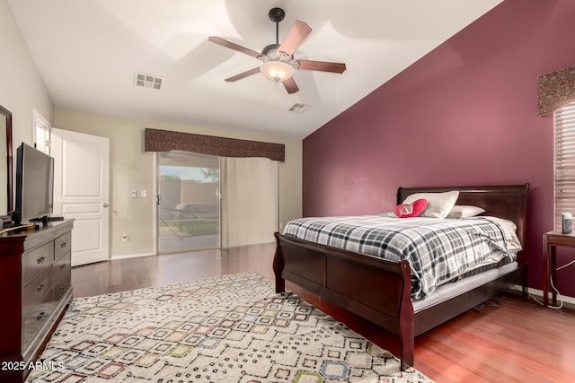 bedroom featuring visible vents, access to outside, vaulted ceiling, and wood finished floors