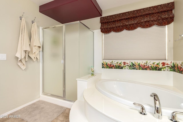 bathroom with a bath, tile patterned floors, a stall shower, and baseboards