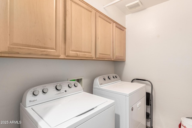 laundry room with visible vents, washing machine and dryer, and cabinet space