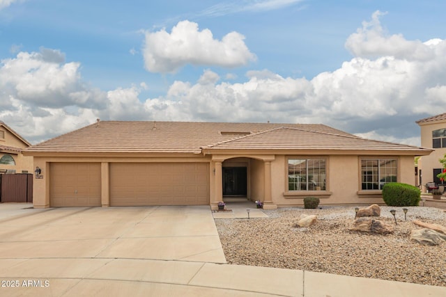 view of front of house featuring a tiled roof, an attached garage, stucco siding, and concrete driveway