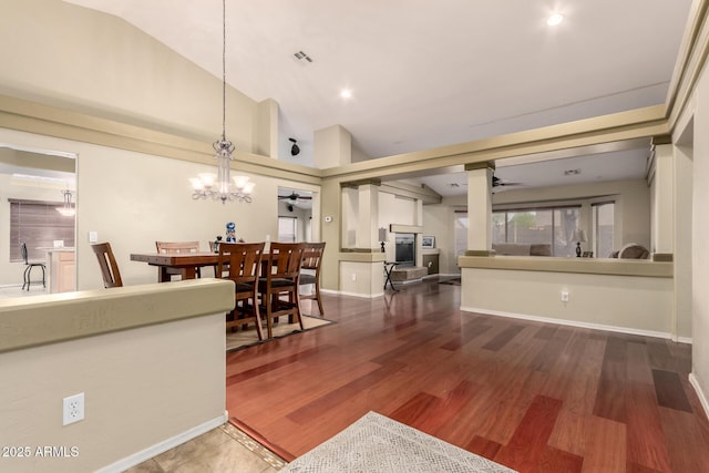 interior space with ceiling fan with notable chandelier, wood finished floors, baseboards, and visible vents
