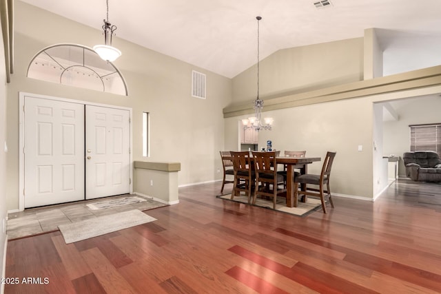 dining area with a chandelier, wood finished floors, high vaulted ceiling, and visible vents