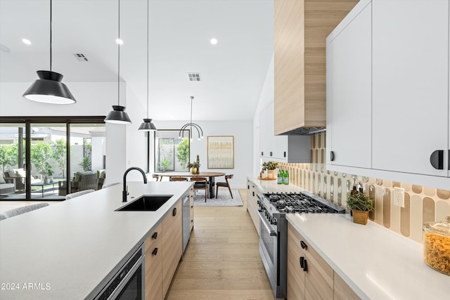 kitchen with sink, white cabinetry, pendant lighting, stainless steel appliances, and light hardwood / wood-style floors