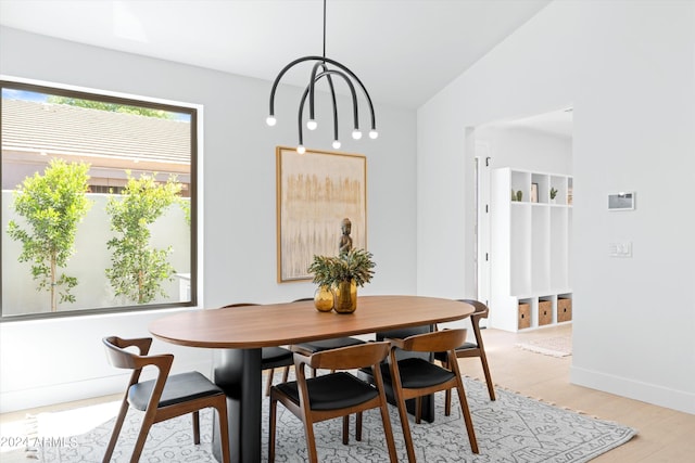 dining space with vaulted ceiling, light hardwood / wood-style flooring, and a notable chandelier