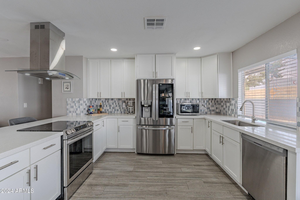 kitchen with sink, island exhaust hood, light hardwood / wood-style floors, stainless steel appliances, and white cabinets