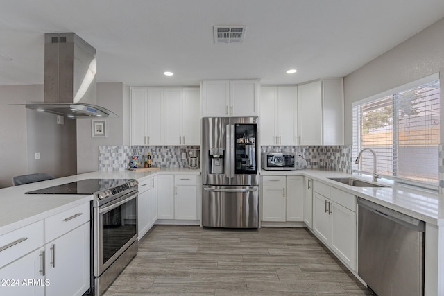 kitchen with sink, island exhaust hood, light hardwood / wood-style floors, stainless steel appliances, and white cabinets