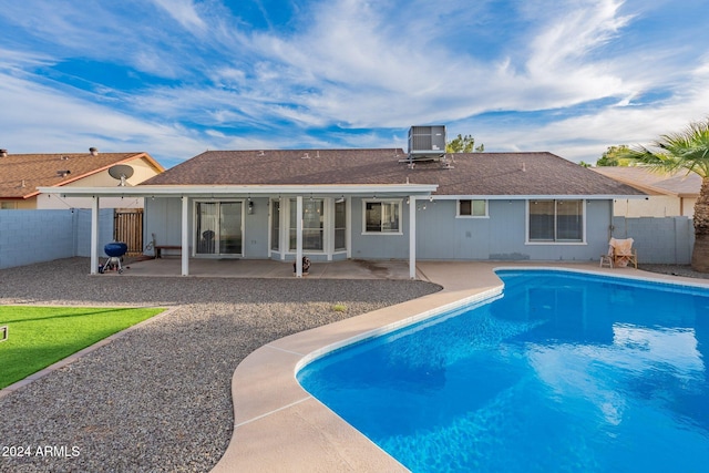 rear view of house featuring cooling unit, a patio, and a fenced in pool