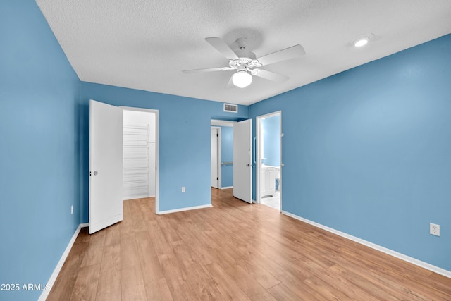 unfurnished bedroom featuring light wood-style floors, baseboards, visible vents, and a textured ceiling