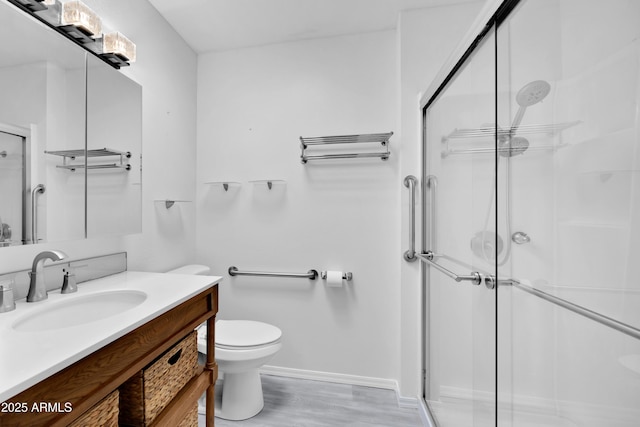 bathroom with toilet, a stall shower, wood finished floors, and vanity