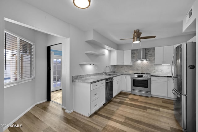 kitchen featuring a sink, white cabinetry, appliances with stainless steel finishes, wall chimney range hood, and open shelves