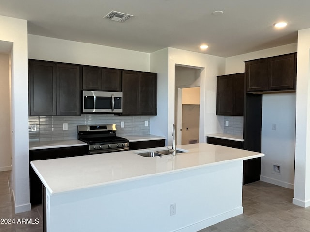 kitchen with a center island with sink, sink, stainless steel appliances, and tasteful backsplash