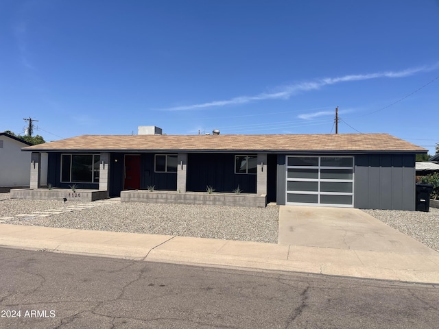 8520 E Mackenzie Dr, Scottsdale, AZ 85251 - view of front of home featuring a garage, covered porch, concrete driveway, and board and batten siding