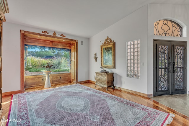 entrance foyer with french doors, vaulted ceiling, and hardwood / wood-style floors