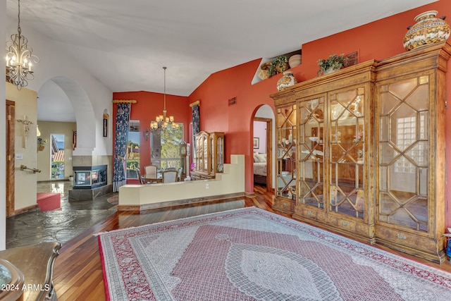 entrance foyer with an inviting chandelier, lofted ceiling, a tiled fireplace, and hardwood / wood-style flooring