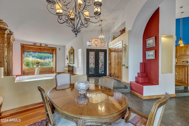 dining area with a notable chandelier, lofted ceiling, hardwood / wood-style flooring, and french doors