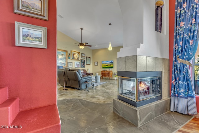 living room with ceiling fan, a fireplace, vaulted ceiling, and wood-type flooring