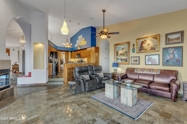 living room with high vaulted ceiling and ceiling fan with notable chandelier