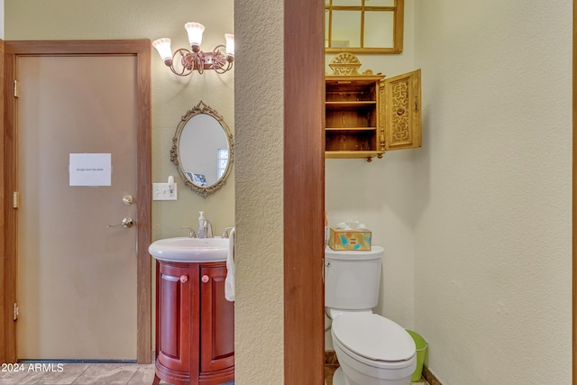 bathroom featuring an inviting chandelier, vanity, toilet, and tile patterned floors