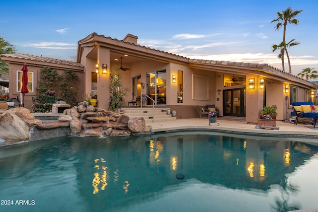 pool at dusk featuring a patio, a hot tub, and ceiling fan