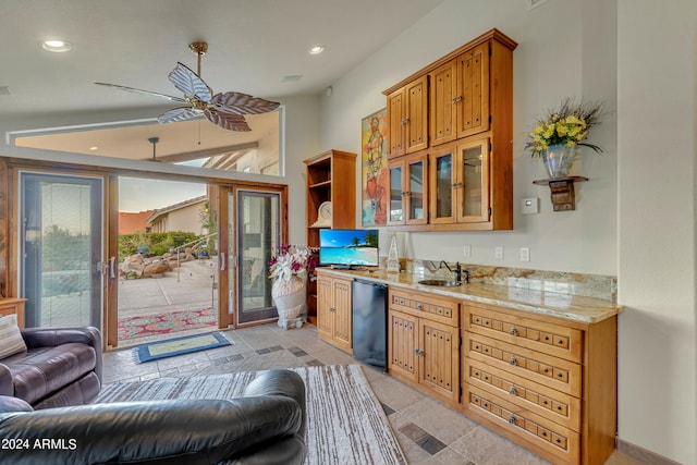 kitchen featuring ceiling fan, light stone countertops, and sink