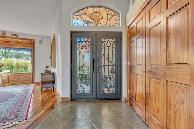 foyer featuring a healthy amount of sunlight, lofted ceiling, dark wood-type flooring, and french doors