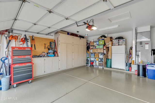 garage with white refrigerator, a garage door opener, and heating unit