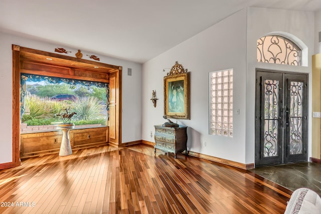 foyer featuring french doors, high vaulted ceiling, wood-type flooring, and a healthy amount of sunlight