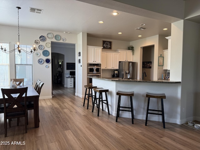 3765 N Denny Way, Buckeye, AZ 85396 - kitchen featuring stainless steel appliances, a chandelier, white cabinets, wood finished floors, and dark stone counters
