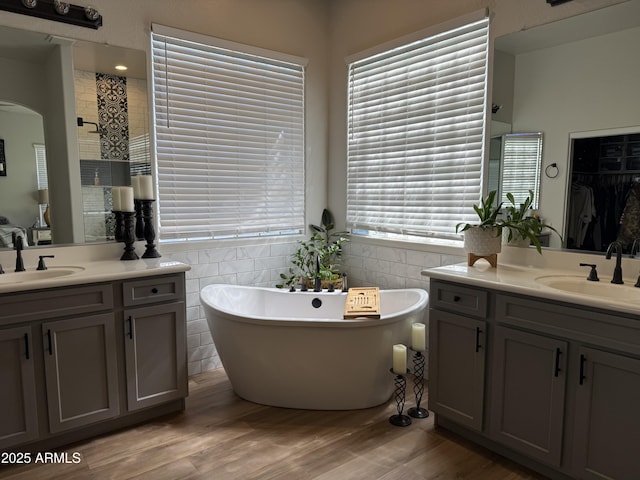 3765 N Denny Way, Buckeye, AZ 85396 - bathroom with two vanities, a freestanding tub, tile walls, wood finished floors, and a spacious closet