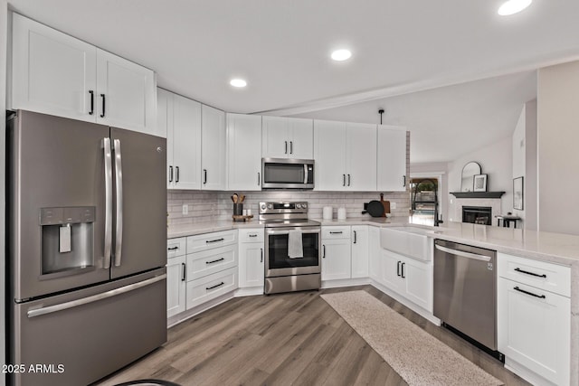 kitchen featuring backsplash, kitchen peninsula, sink, white cabinetry, and stainless steel appliances