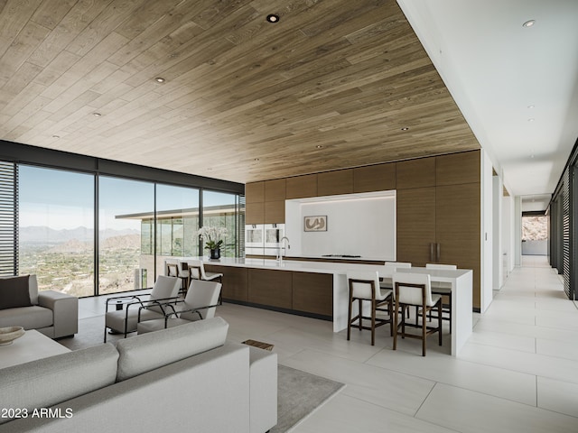 living area with recessed lighting, a wall of windows, wood ceiling, light tile patterned flooring, and a mountain view