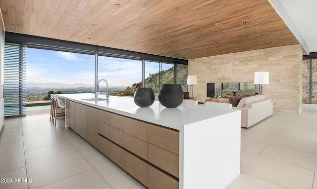 kitchen featuring a spacious island, sink, wood ceiling, and expansive windows